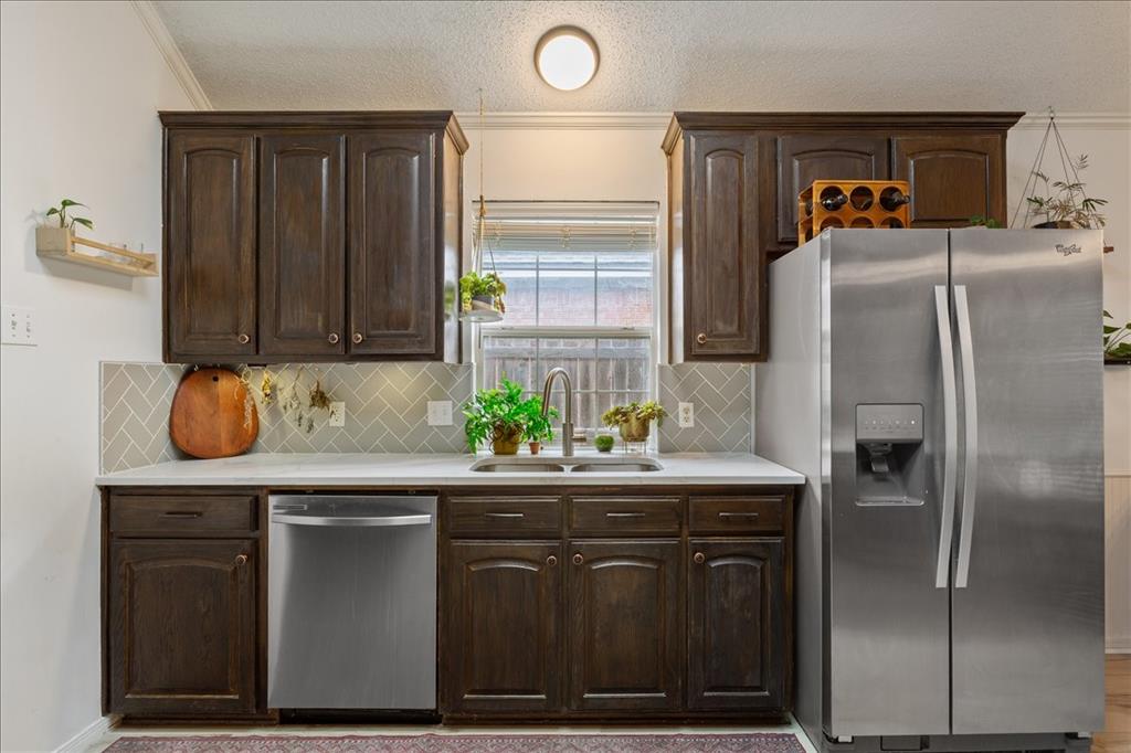 Kitchen featuring dark wood cabinetry, light countertops, and a herringbone-patterned tile backsplash