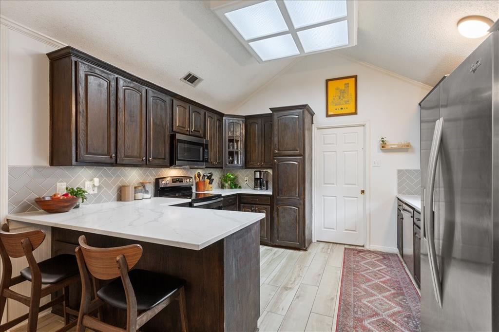 Kitchen featuring dark wood cabinetry, light countertops, and a white subway tile backsplash in a herringbone pattern
