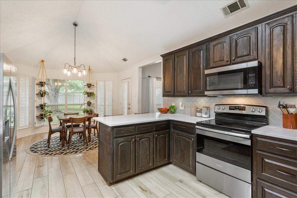 Kitchen featuring dark wood cabinetry, light countertops, and stainless steel appliances