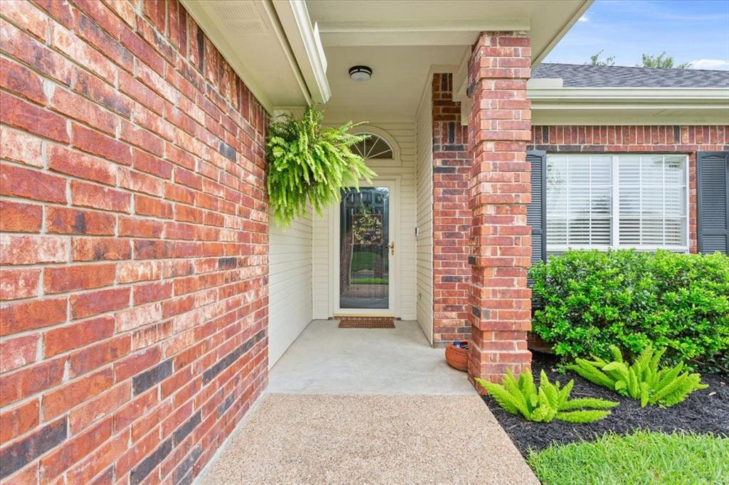 Brick exterior with covered entryway, arched transom window, and a concrete pathway Brick exterior with covered entryway, arched transom window, and a concrete pathway
