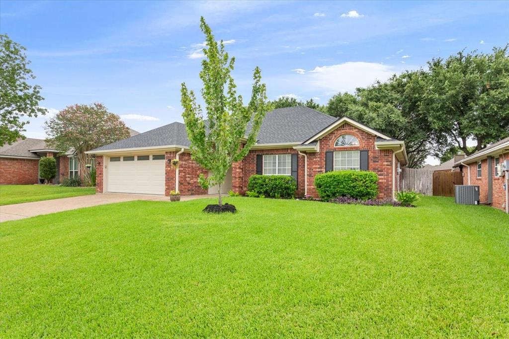 Traditional brick-front residence featuring a two-car garage with a panel door, a dark shingle roof, and a meticulously maintained front lawn Traditional brick-front residence featuring a two-car garage with a panel door, a dark shingle roof, and a meticulously maintained front lawn