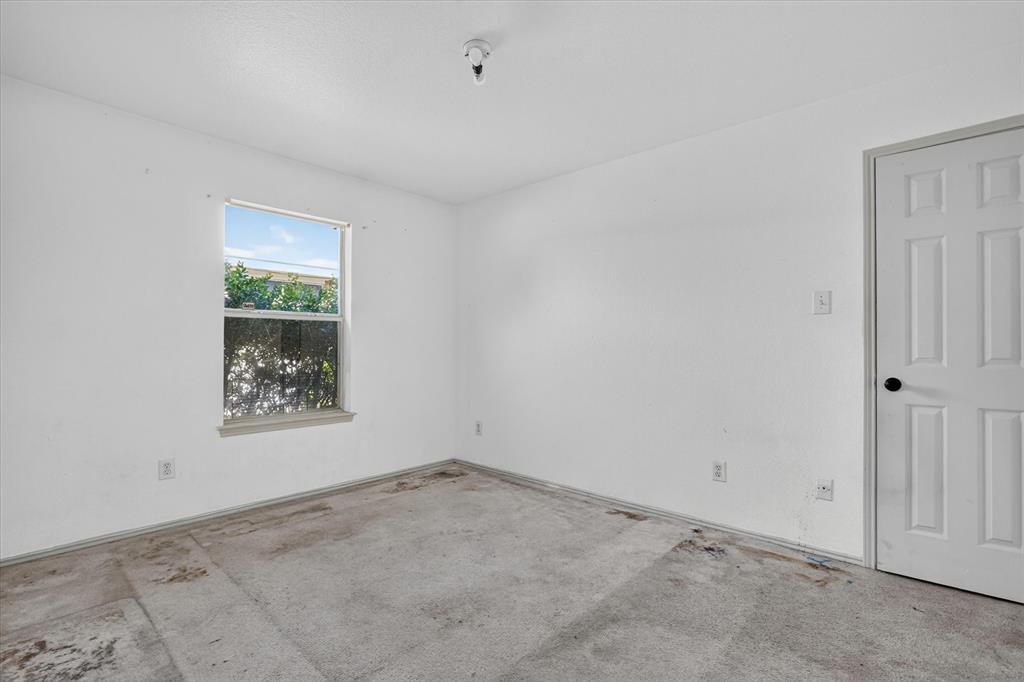 Windowed interior space with a paneled door and exposed concrete flooring