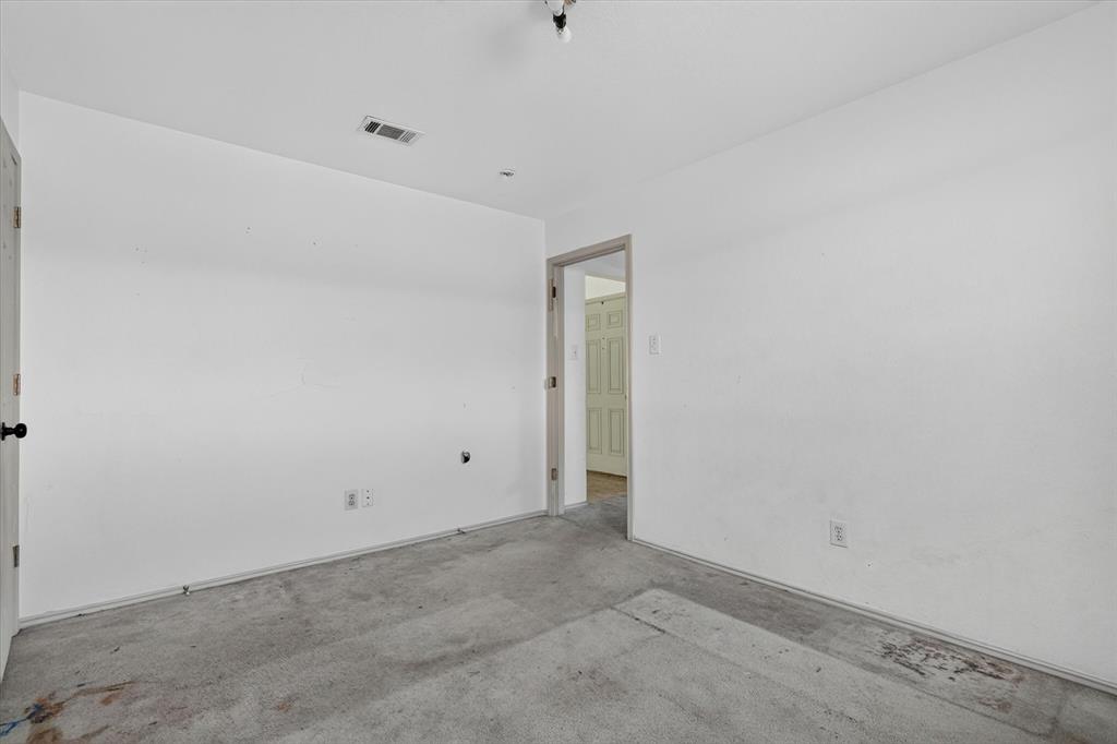 White-painted interior walls with a gray carpeted floor, featuring a doorway leading to another interior space
