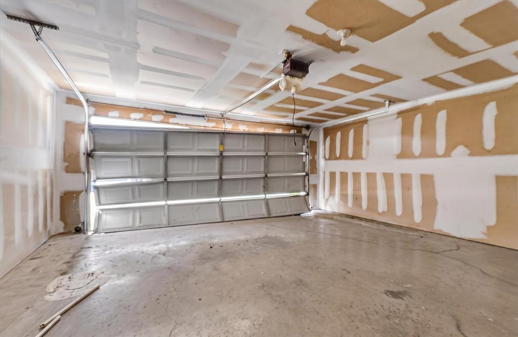 Spacious garage featuring a concrete floor, an overhead garage door, and visible ceiling joists
