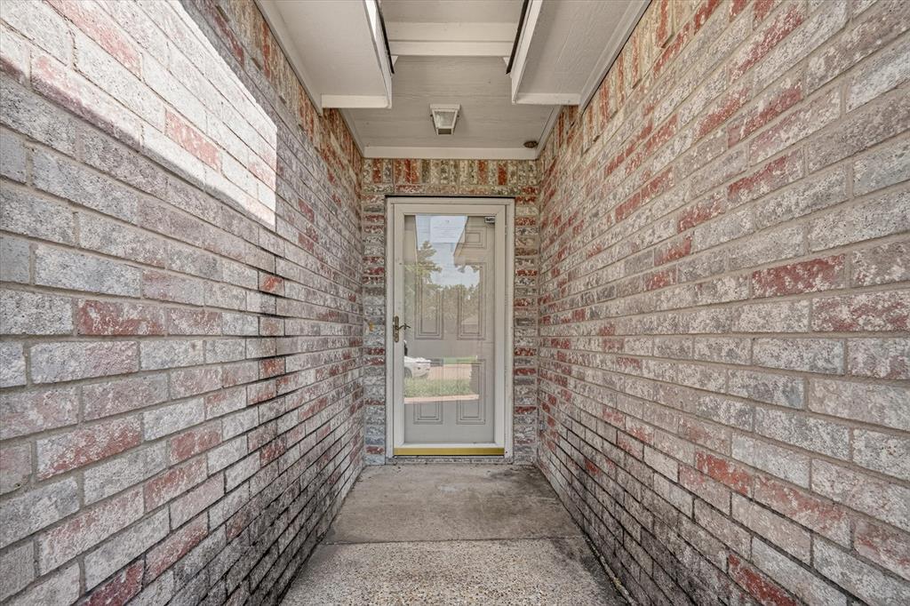 Entryway featuring mixed-tone brick siding and a storm door