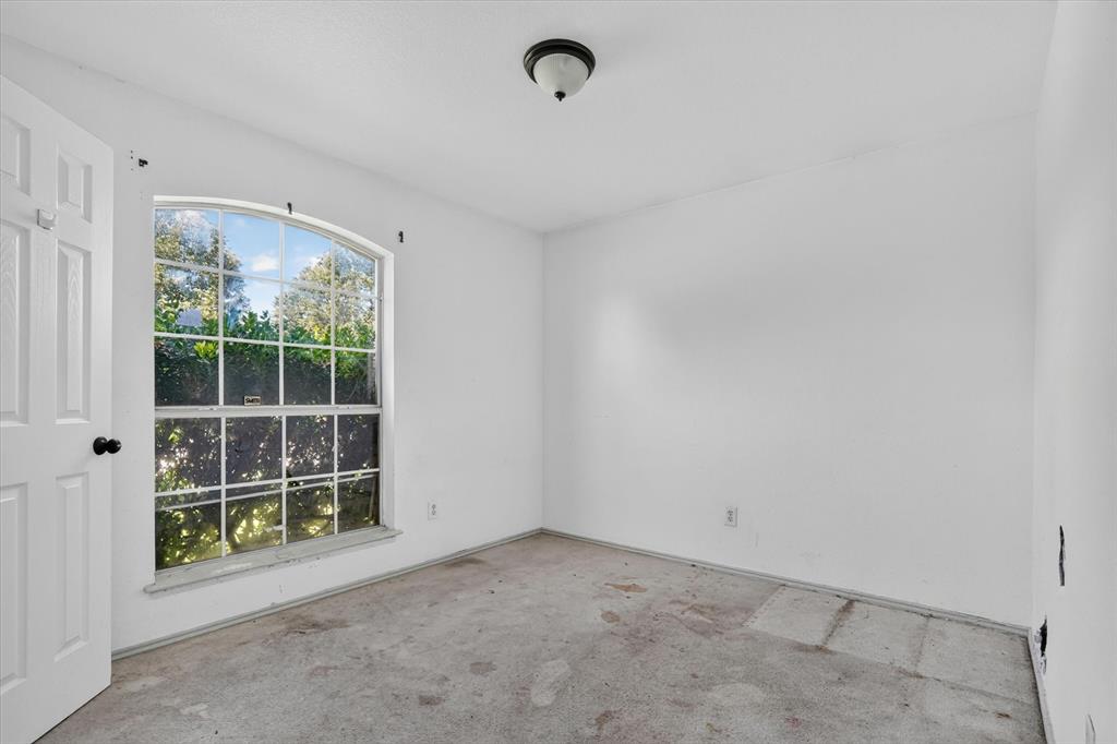 Room featuring a large arched window with multiple panes, white walls, and a ceiling-mounted light fixture