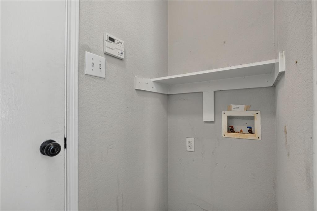 Dedicated laundry space featuring a built-in white shelf, utility hookups, and electrical outlet