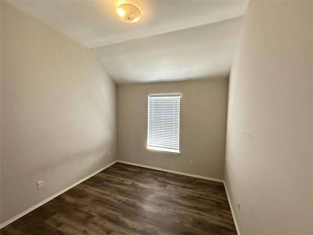 Room featuring wood-finish flooring, neutral wall tones, a rectangular window with blinds, and a flush mount ceiling light