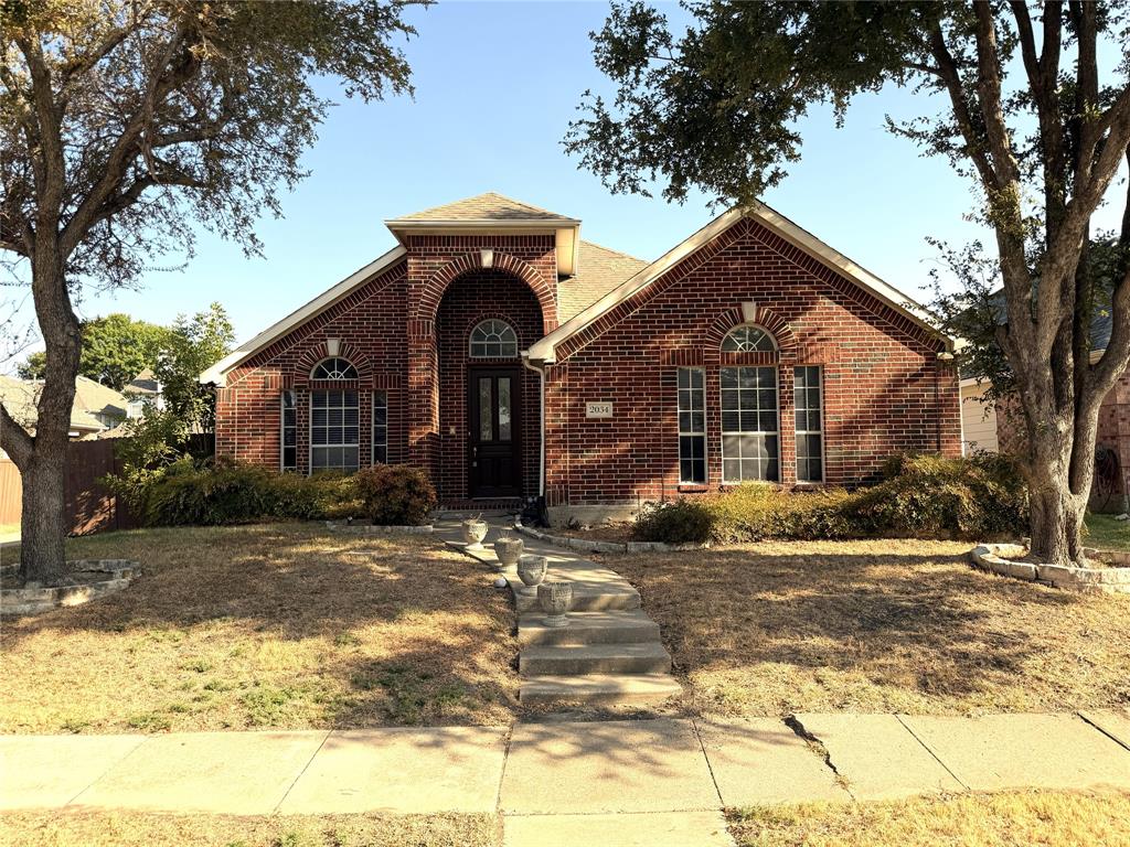 Brick facade with arched entry, complementing arched windows, and mature trees Brick facade with arched entry, complementing arched windows, and mature trees