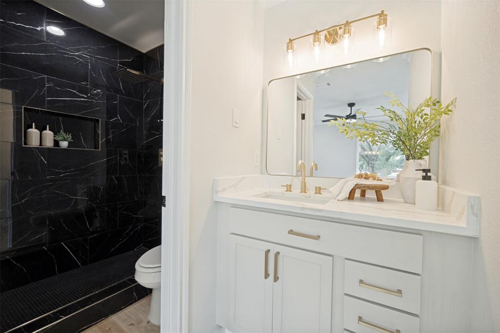 White vanity with gold-tone hardware, rectangular mirror, and a gold-tone light fixture