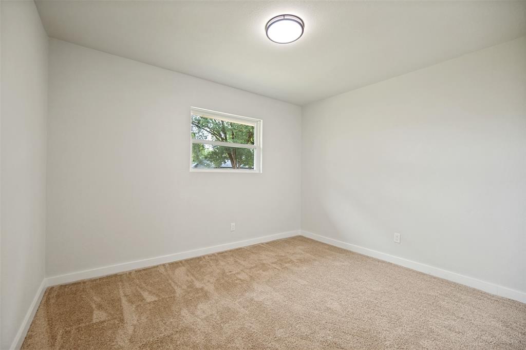Bright room featuring neutral-toned carpet, a double-hung window, and a flush-mount ceiling light fixture