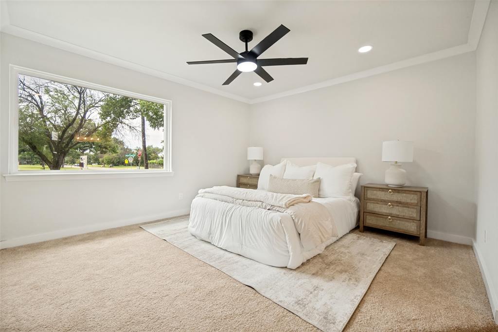 Spacious room featuring a large window, neutral carpeting, a modern black ceiling fan, and recessed lighting
