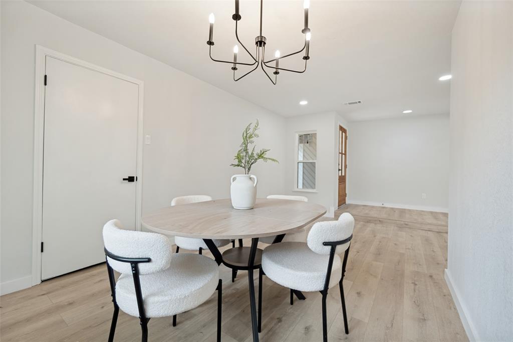 Bright interior space with light wood-finish flooring, recessed lighting, and a modern black chandelier