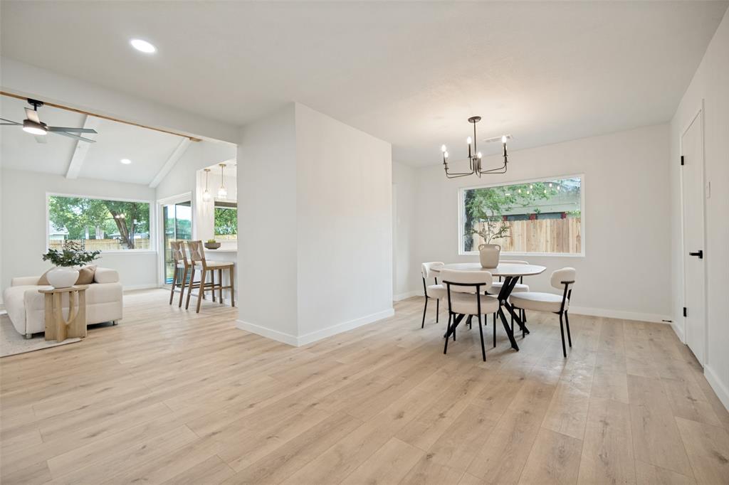 Open-concept living space featuring light wood-finish flooring, white walls, and a modern chandelier