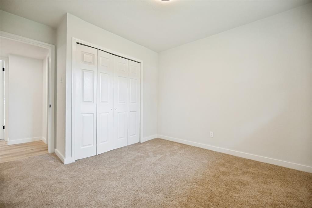 Carpeted room featuring a four-panel bi-fold closet, white walls, and white baseboards