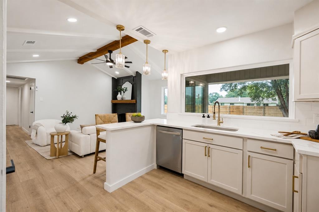 Open-concept kitchen and living area featuring a vaulted ceiling with exposed wood beam, recessed lighting, and wood-finish flooring