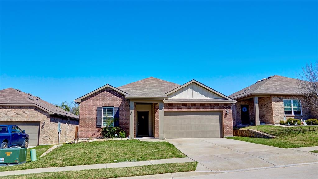 Brick exterior with gabled roofline, front-facing garage, concrete driveway, and covered entry