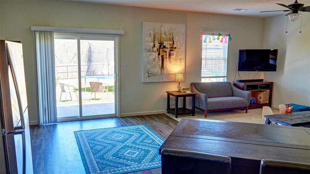 Wood-finish flooring, sliding glass patio door, ceiling fan, and window with blinds