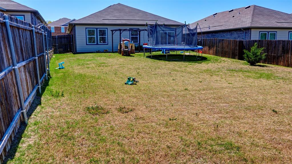Expansive backyard featuring a privacy fence and a rear exterior with a sliding glass door