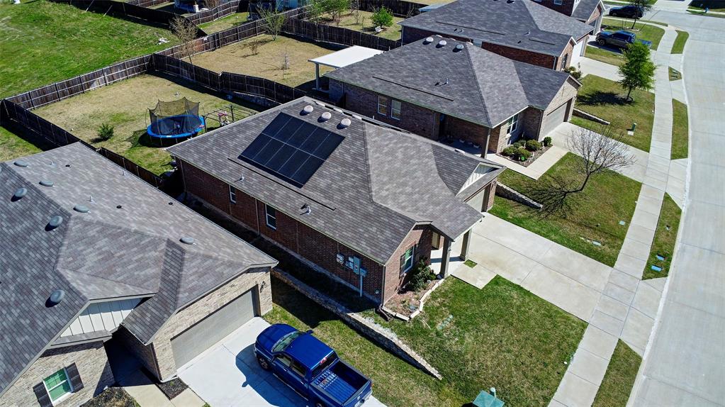 Brick exterior with an attached garage, featuring solar panels on the roof and a fenced backyard