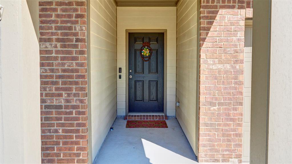 Brick and siding exterior facade with a dark paneled entry door and concrete porch