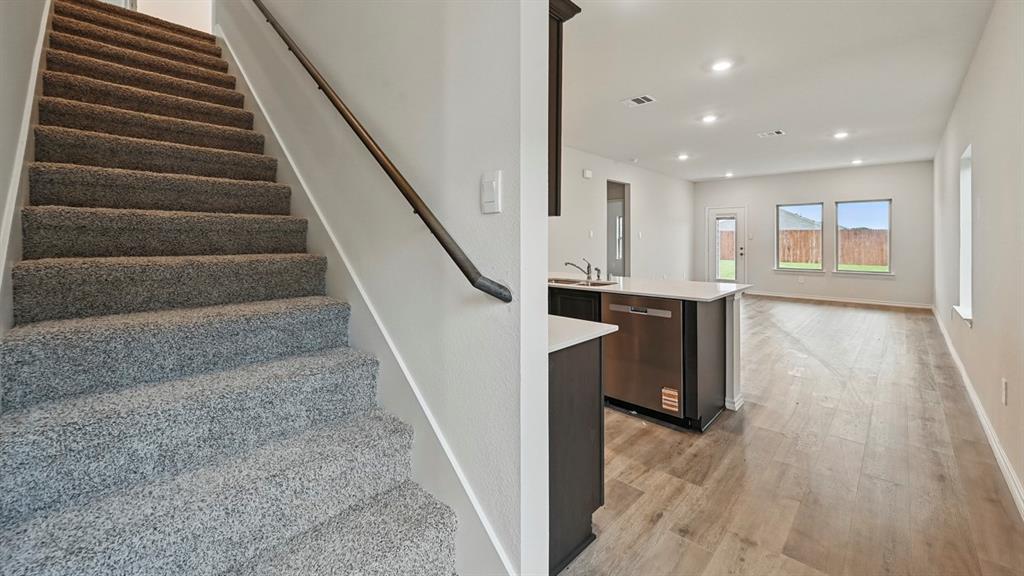 Open-concept living space featuring wood-finish flooring, recessed lighting, and an island kitchen with a stainless steel dishwasher