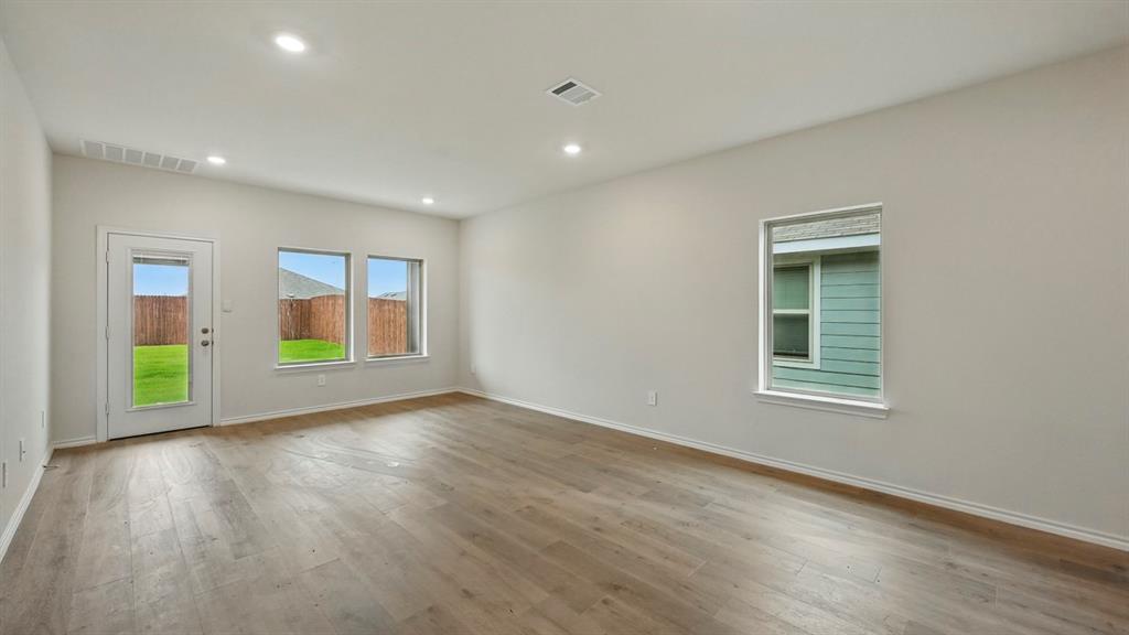 Spacious room featuring wood-finish flooring, recessed lighting, and ample natural light from multiple windows
