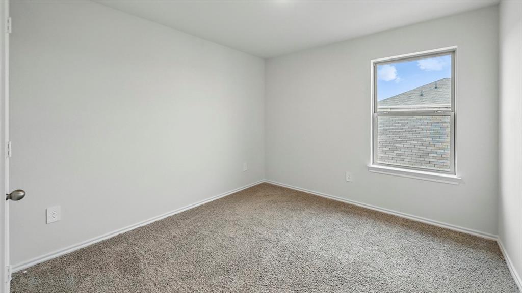 Carpeted interior room featuring a single window with white trim, light gray walls, and white baseboards