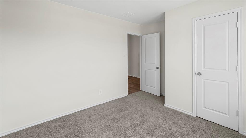 Neutral-toned room featuring gray carpeting, white baseboards, and two white two-panel doors with brushed nickel hardware
