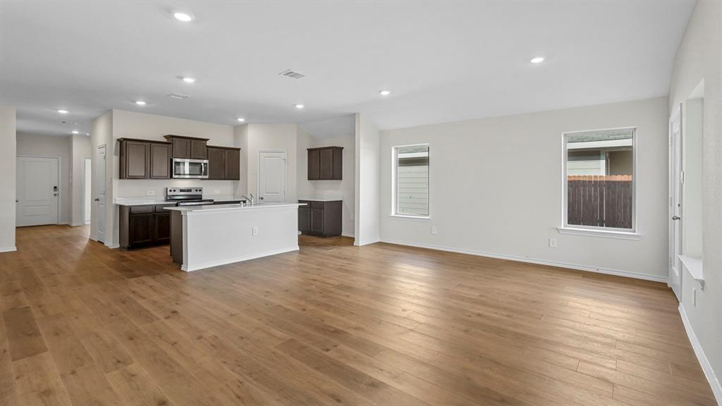 Open-concept living area featuring wood-finish flooring, recessed lighting, and multiple windows