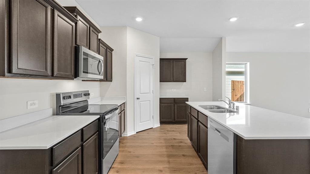 Modern kitchen featuring dark wood cabinetry, light-toned countertops, and wood-finish flooring