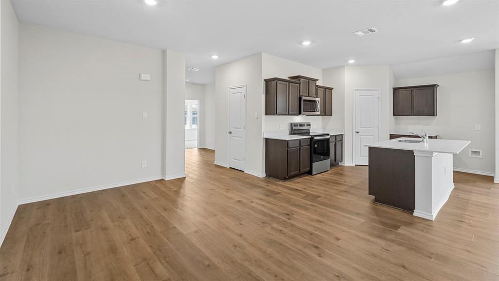 Open-concept living space featuring wood-finish flooring, recessed lighting, and a kitchen with dark wood cabinetry