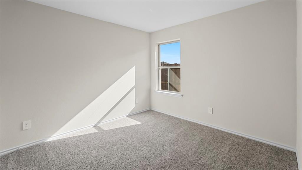 Neutral-toned room featuring a single window, light-colored walls, gray carpeting, and white baseboards