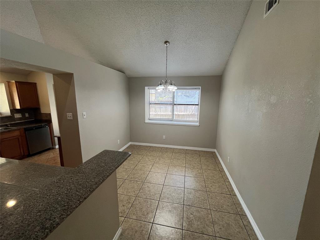 Tile flooring with a neutral finish, a single window with blinds, and a built-in breakfast bar with a granite-finish countertop Tile flooring with a neutral finish, a single window with blinds, and a built-in breakfast bar with a granite-finish countertop