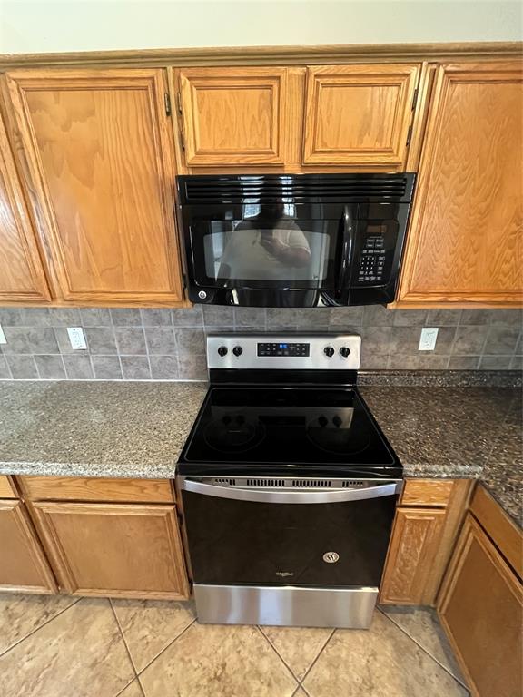 Stainless steel and black range, coordinating over-the-range microwave, granite-look countertops, subway tile backsplash, and light wood-finish cabinetry Stainless steel and black range, coordinating over-the-range microwave, granite-look countertops, subway tile backsplash, and light wood-finish cabinetry