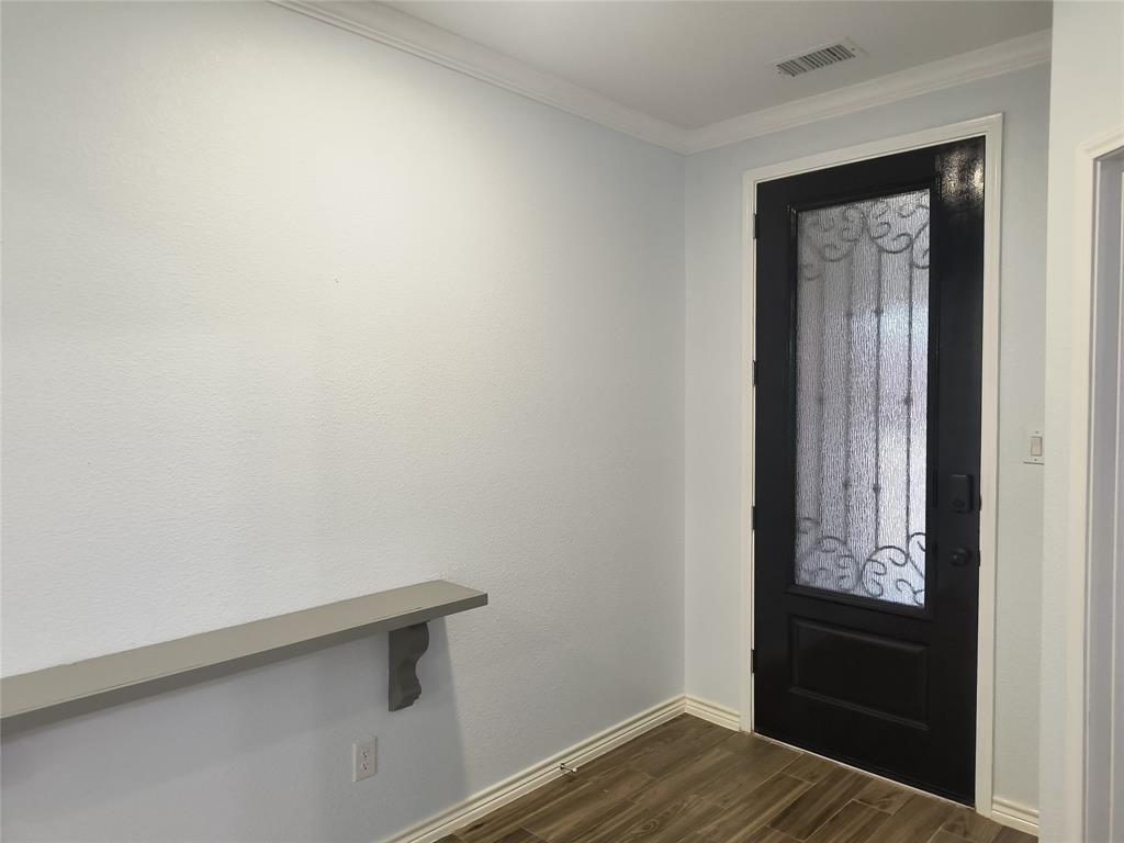 Black entry door with frosted glass and decorative ironwork, complemented by light wood-finish flooring