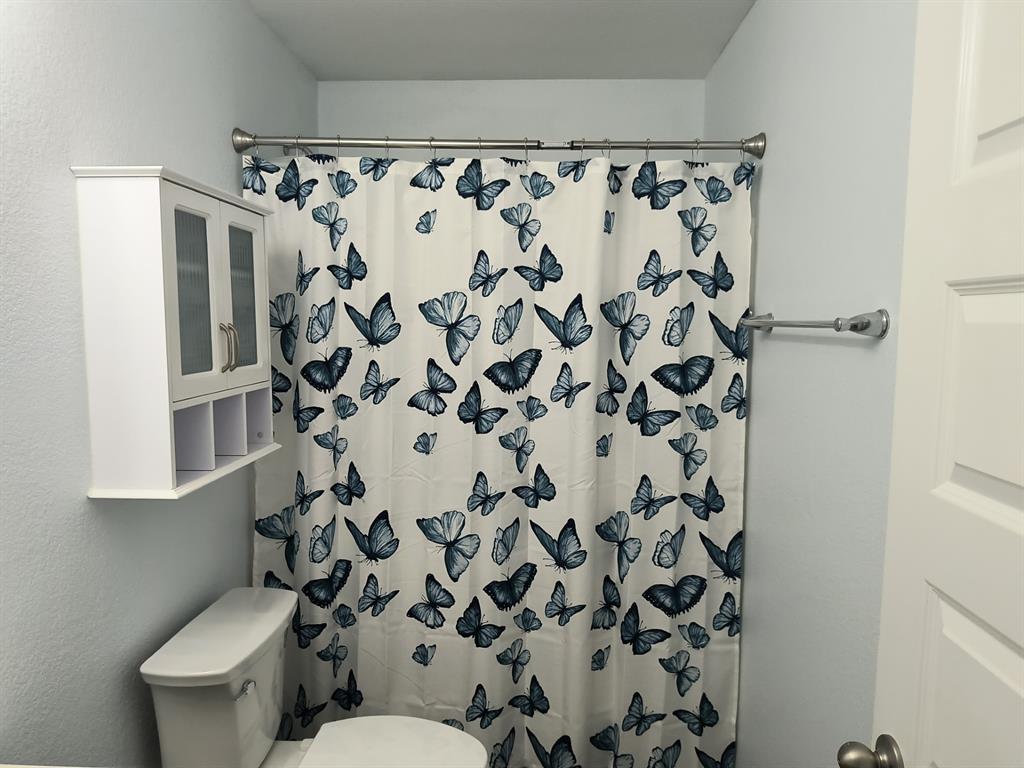 Bathroom featuring a wall-mounted cabinet with glass-front doors, open cubby storage, and a white toilet
