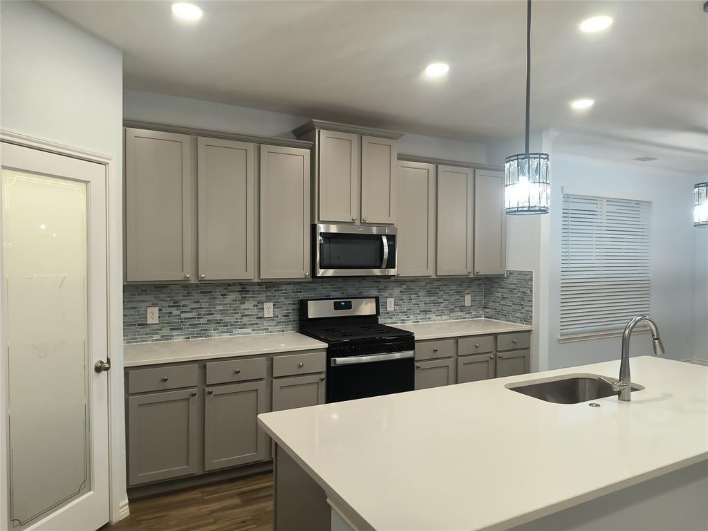 Contemporary kitchen featuring light gray cabinetry, a mosaic tile backsplash, and light-toned countertops
