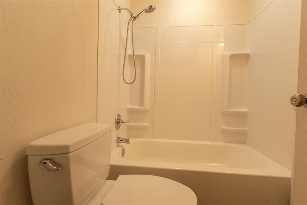 White bathtub and shower combination featuring a chrome shower head and faucet