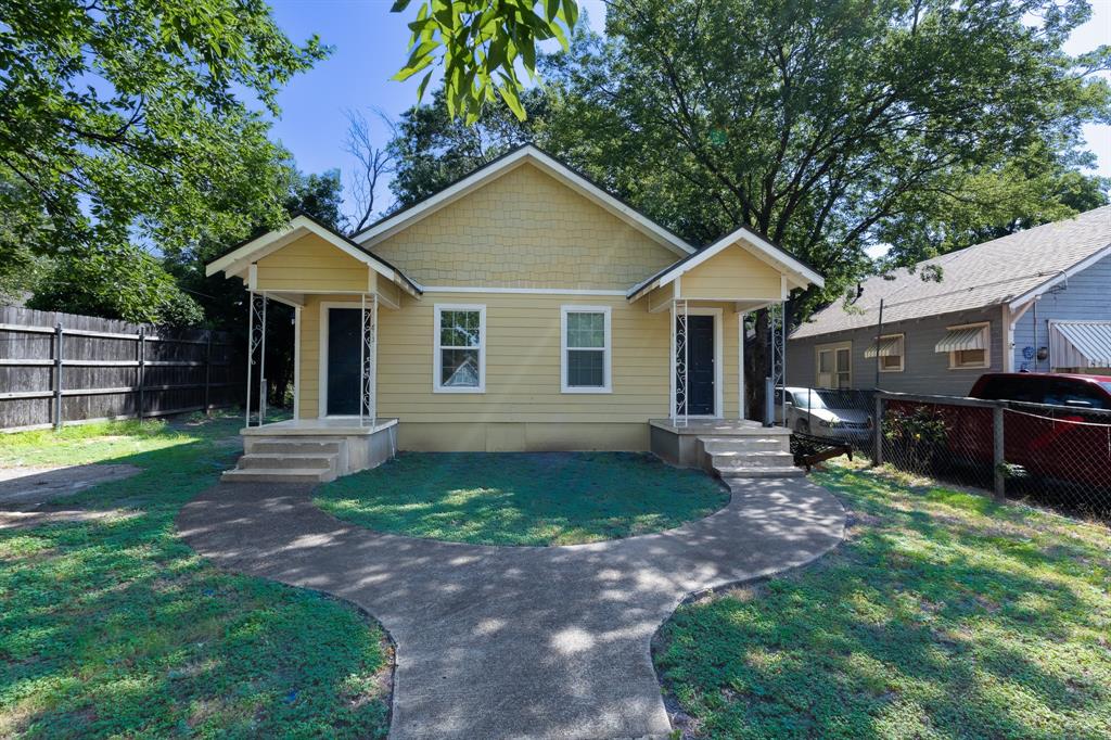 Duplex property featuring a light yellow exterior with white trim, two separate entryways with covered porches, and a shared curved concrete walkway