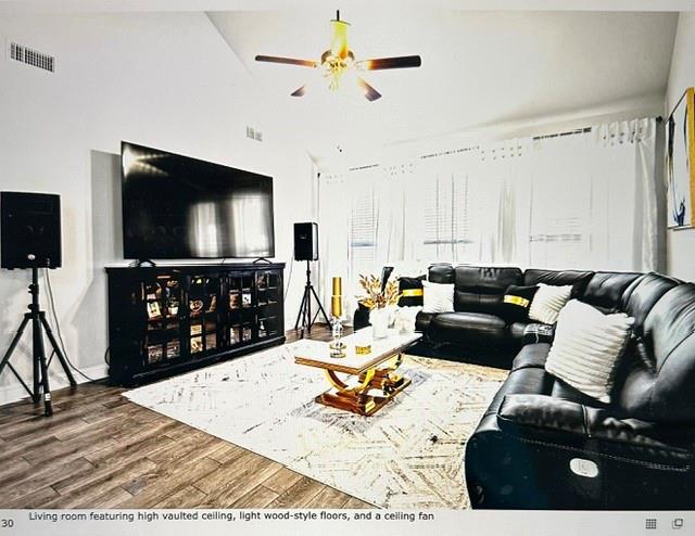 Living room featuring high vaulted ceiling, light wood-style floors, and a ceiling fan