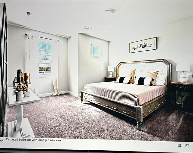 Carpeted bedroom featuring multiple windows, recessed lighting, and a neutral color palette
