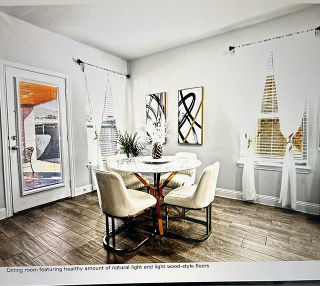 Dining area featuring wood-finish flooring, two large windows with blinds, and a glass-paneled door