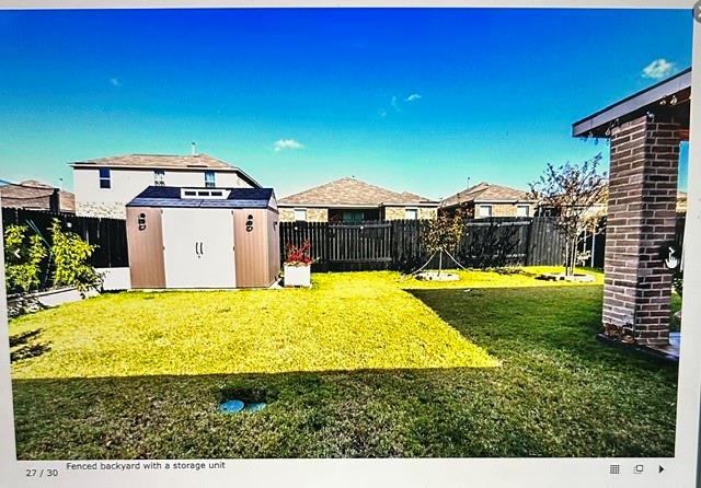 Expansive green lawn with a brown and white storage shed, surrounded by dark wood privacy fencing