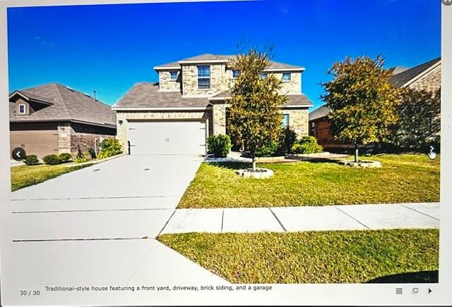 Traditional-style house featuring a front yard, driveway, brick siding, and a garage Traditional-style house featuring a front yard, driveway, brick siding, and a garage
