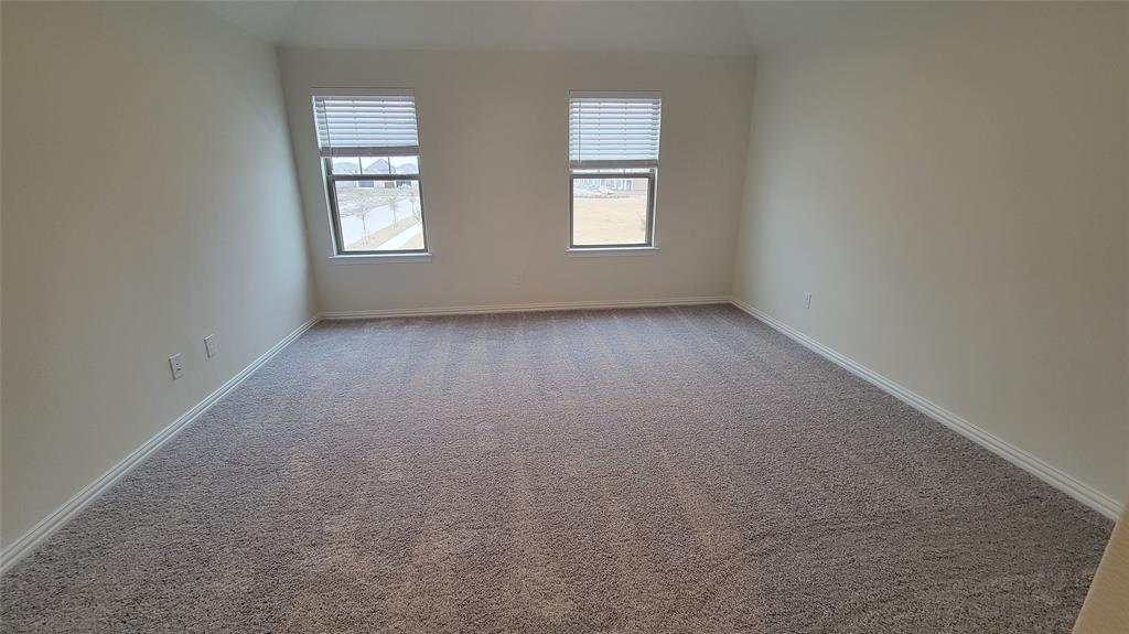 Spacious room featuring neutral wall paint, two windows with blinds, and light gray carpeting