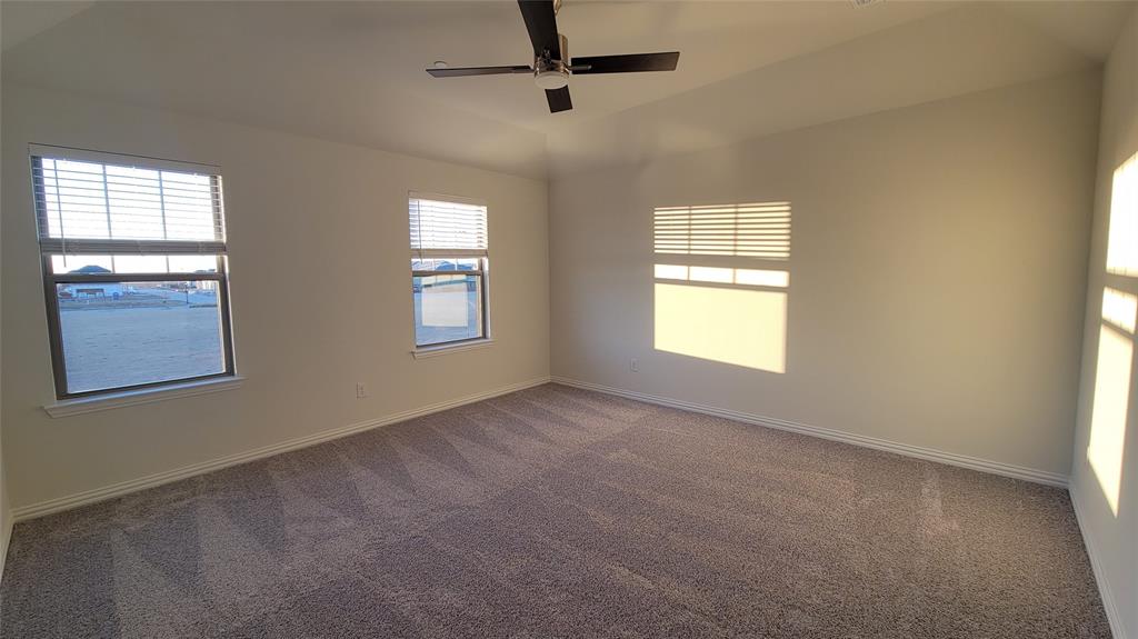 Spacious room featuring vaulted ceilings, neutral-toned walls, and plush carpeting