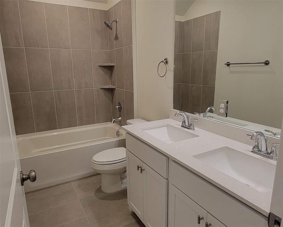 Bathroom with dual vanity featuring built-in sinks, a solid surface countertop, and white shaker-style cabinetry