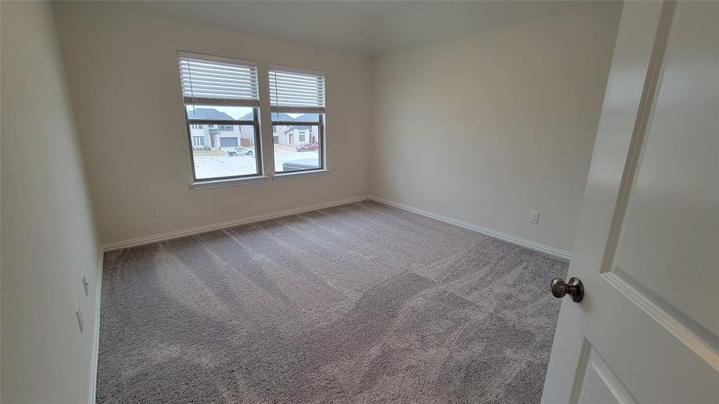 Spacious room featuring neutral carpeting, light-toned walls, and twin windows with horizontal blinds