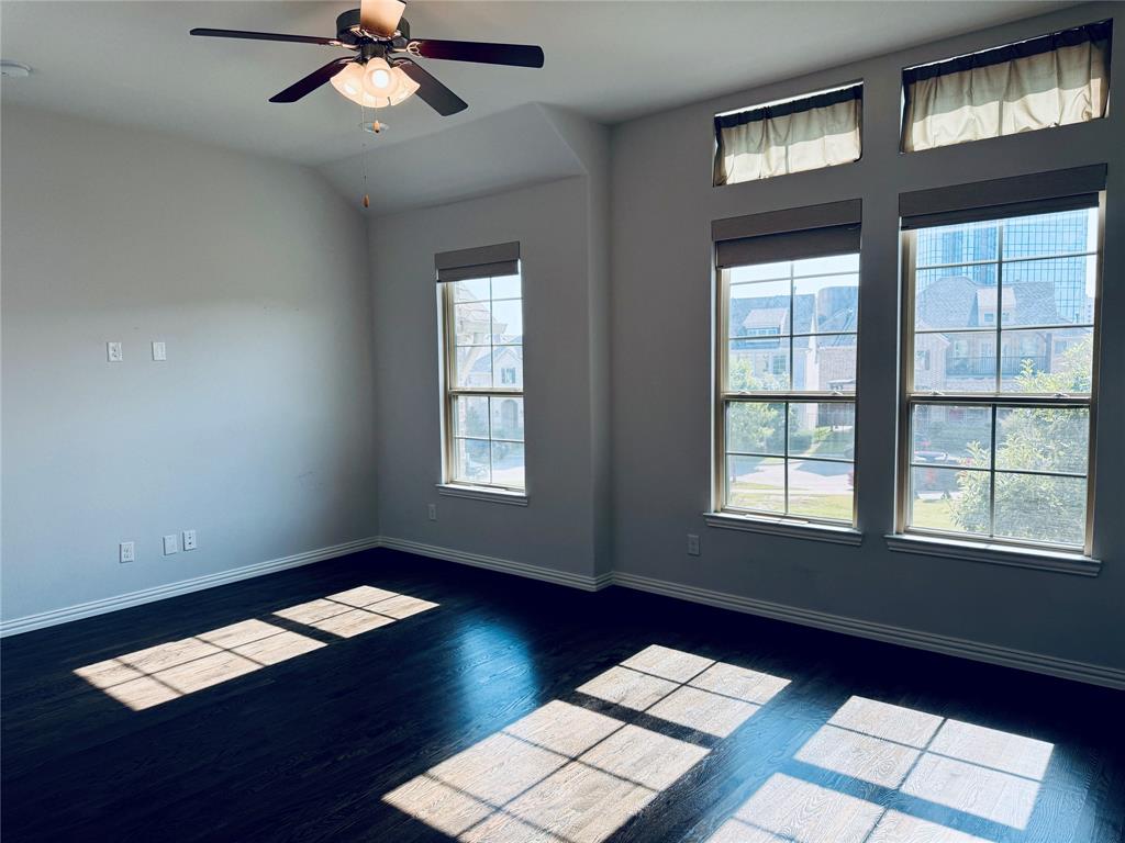 Spacious room featuring dark wood-finish flooring, light neutral-toned walls, and a motorized blinds